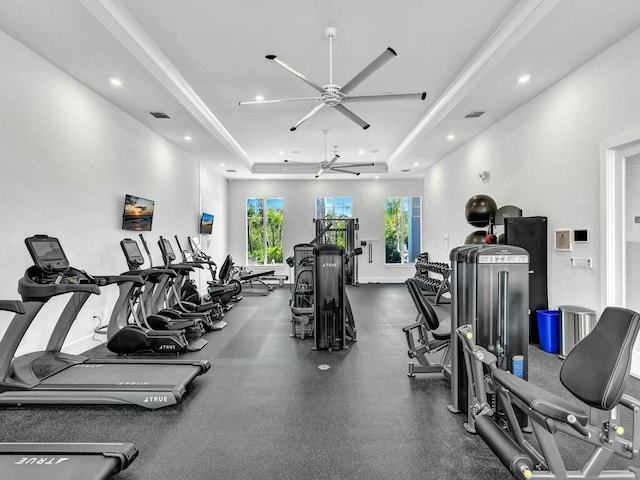 exercise room featuring ceiling fan and a tray ceiling