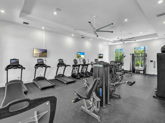 exercise room featuring ceiling fan and a raised ceiling