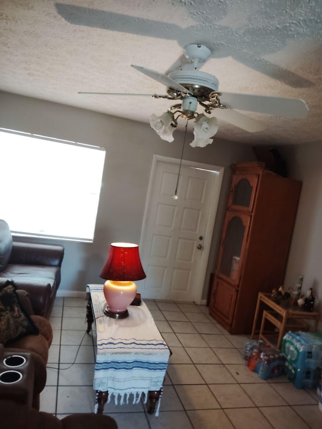 living room featuring light tile patterned flooring, ceiling fan, and a textured ceiling