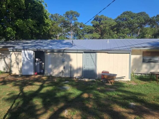 back of house with metal roof and a yard