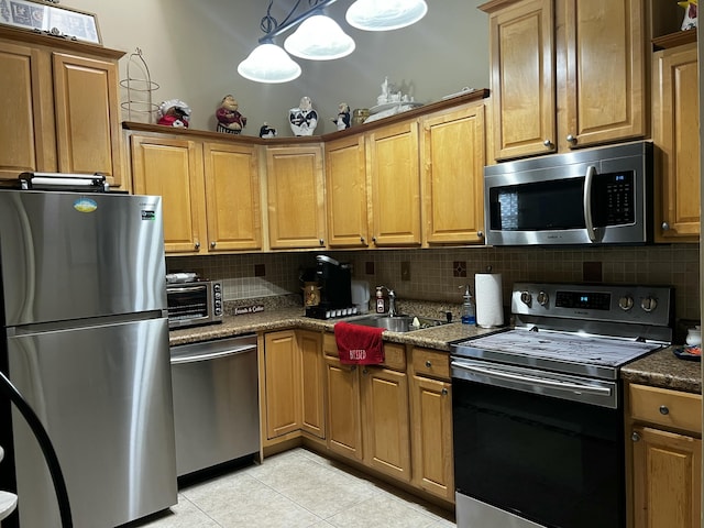 kitchen with appliances with stainless steel finishes, sink, light tile patterned floors, and backsplash