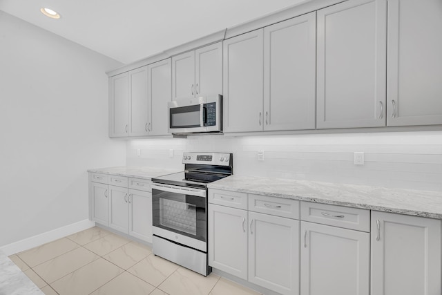 kitchen with white cabinets, appliances with stainless steel finishes, backsplash, and light stone counters