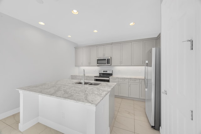 kitchen featuring light stone countertops, appliances with stainless steel finishes, a center island with sink, and sink