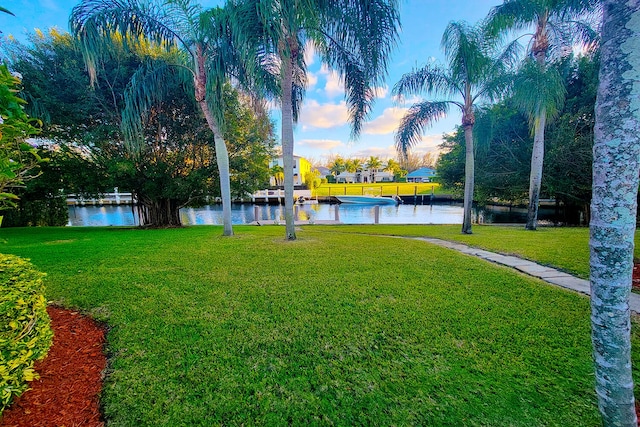 yard at dusk featuring a water view