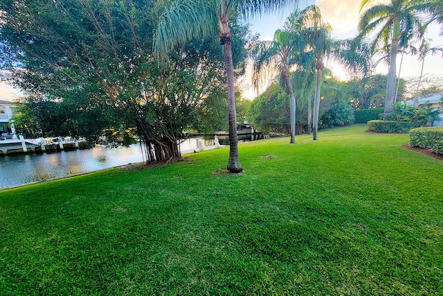 yard at dusk featuring a water view