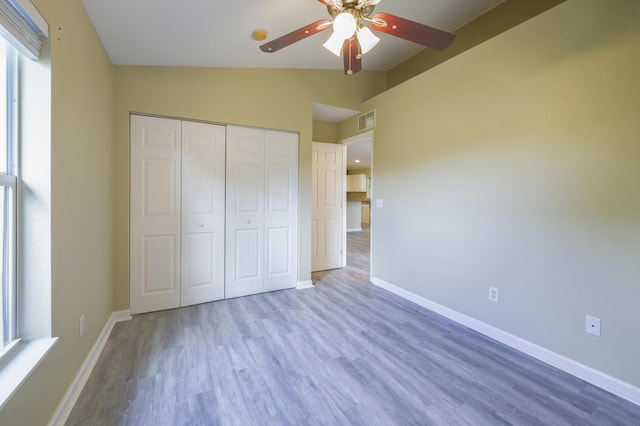 unfurnished bedroom with light hardwood / wood-style floors, a closet, lofted ceiling, and ceiling fan