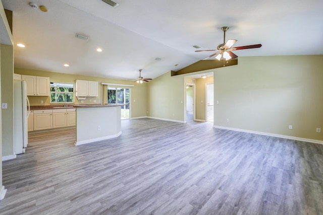 unfurnished living room with light wood-type flooring, vaulted ceiling, ceiling fan, and sink