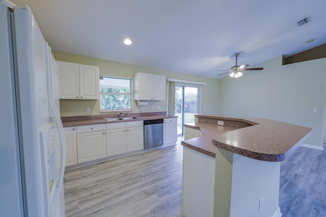 kitchen featuring dishwasher, white fridge with ice dispenser, a kitchen island, vaulted ceiling, and white cabinets