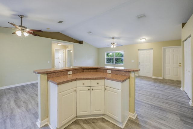 kitchen with vaulted ceiling, ceiling fan, a center island, light hardwood / wood-style floors, and white cabinetry