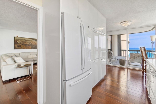 kitchen featuring floor to ceiling windows, white refrigerator, dark hardwood / wood-style flooring, and a textured ceiling