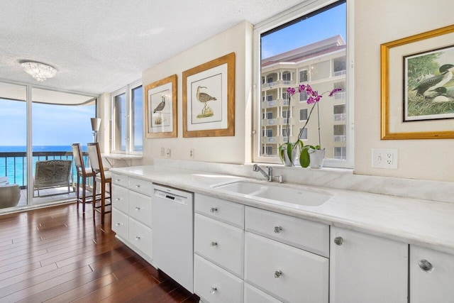 kitchen with dishwasher, white cabinets, a water view, sink, and a textured ceiling