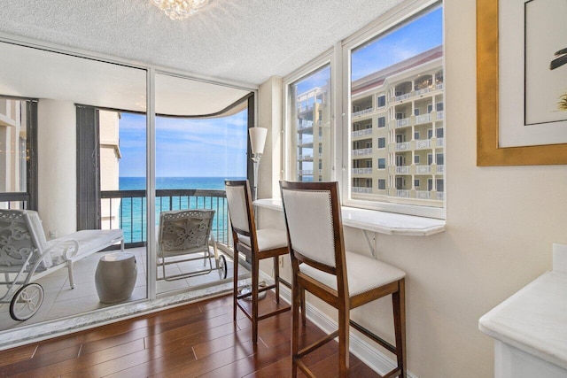 dining room featuring expansive windows, a water view, a wealth of natural light, and dark hardwood / wood-style floors