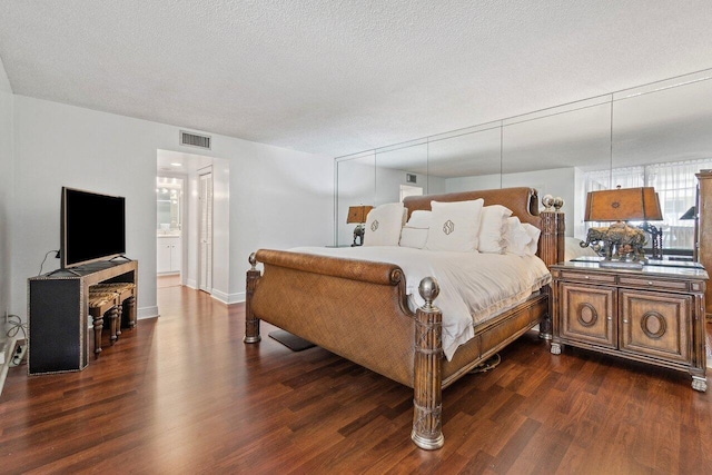 bedroom featuring a textured ceiling, dark hardwood / wood-style floors, and ensuite bath