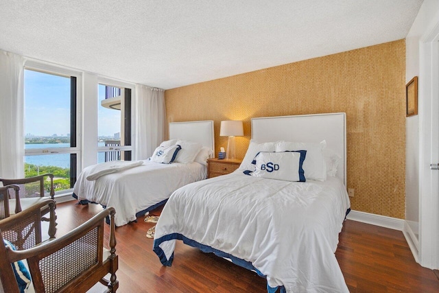 bedroom featuring dark hardwood / wood-style floors, floor to ceiling windows, and a water view