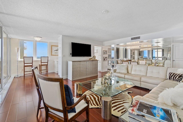 living room with a textured ceiling, dark hardwood / wood-style flooring, and a healthy amount of sunlight