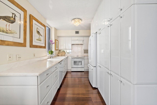 kitchen featuring white appliances, dark wood-type flooring, white cabinets, sink, and a textured ceiling