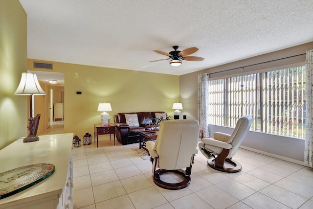 tiled living room featuring ceiling fan and a textured ceiling