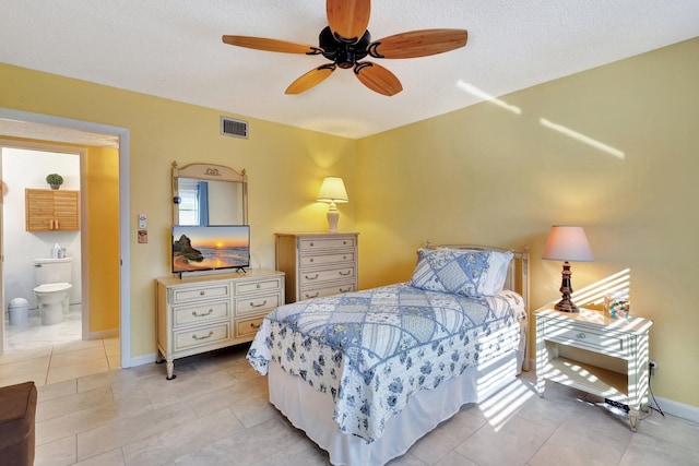 bedroom with ceiling fan, light tile patterned flooring, ensuite bathroom, and a textured ceiling