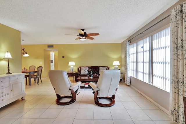 tiled living room with ceiling fan and a textured ceiling