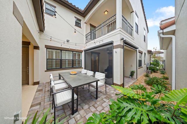 back of property featuring a balcony, a sunroom, and a patio