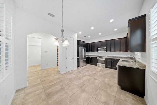 kitchen featuring sink, an inviting chandelier, hanging light fixtures, light stone countertops, and stainless steel appliances