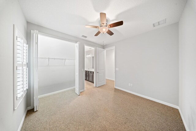 carpeted bedroom with a closet, ensuite bathroom, and ceiling fan