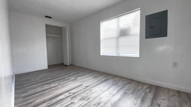 unfurnished bedroom with electric panel, a closet, and light wood-type flooring