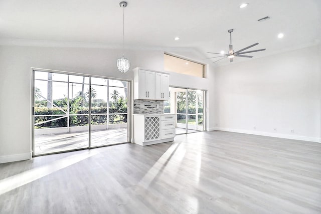 unfurnished living room featuring ceiling fan with notable chandelier, lofted ceiling, and light hardwood / wood-style flooring