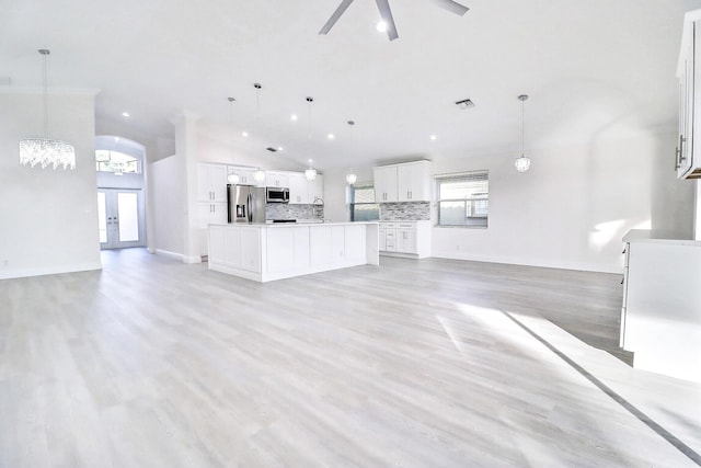 unfurnished living room with ceiling fan, a healthy amount of sunlight, light wood-type flooring, and french doors