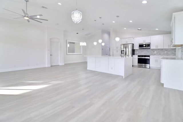 kitchen with a kitchen island, white cabinets, decorative light fixtures, and appliances with stainless steel finishes