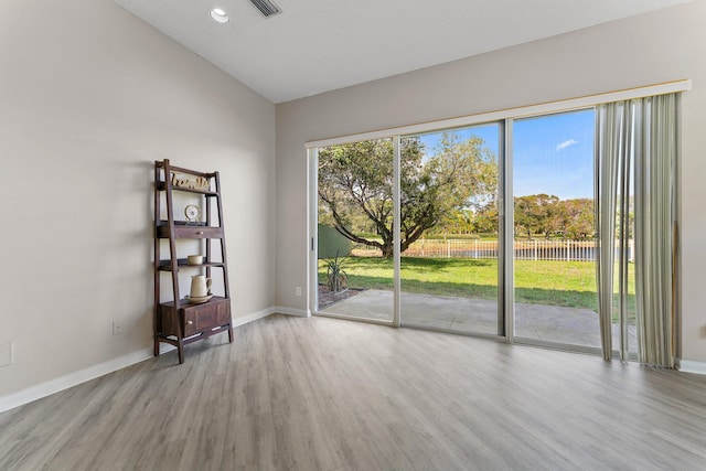 spare room with lofted ceiling and light wood-type flooring