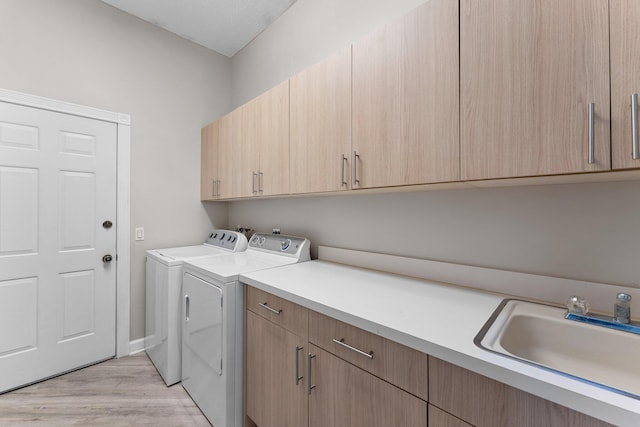 laundry area with cabinets, light wood-type flooring, washer and dryer, and sink