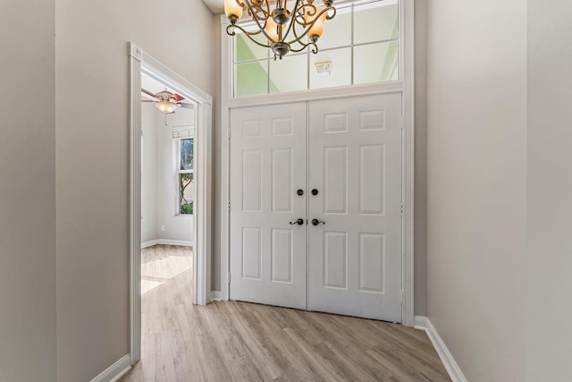 entryway featuring ceiling fan with notable chandelier and light hardwood / wood-style floors