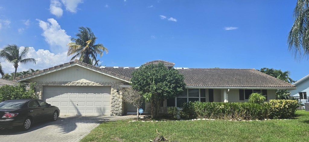 ranch-style house with a garage and a front lawn