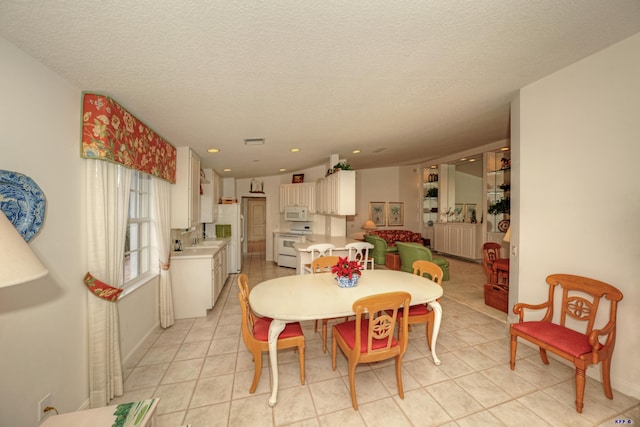 tiled dining space featuring sink and a textured ceiling