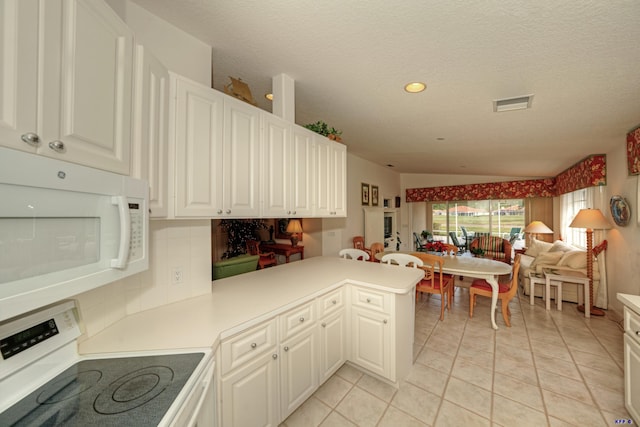 kitchen with light tile patterned floors, kitchen peninsula, lofted ceiling, white cabinets, and range