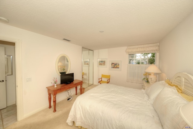 carpeted bedroom featuring a textured ceiling and a closet