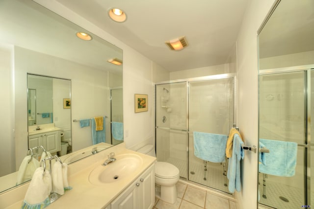 bathroom with tile patterned floors, vanity, walk in shower, and toilet