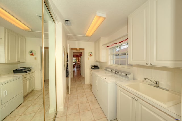 clothes washing area with light tile patterned flooring, cabinets, separate washer and dryer, and sink