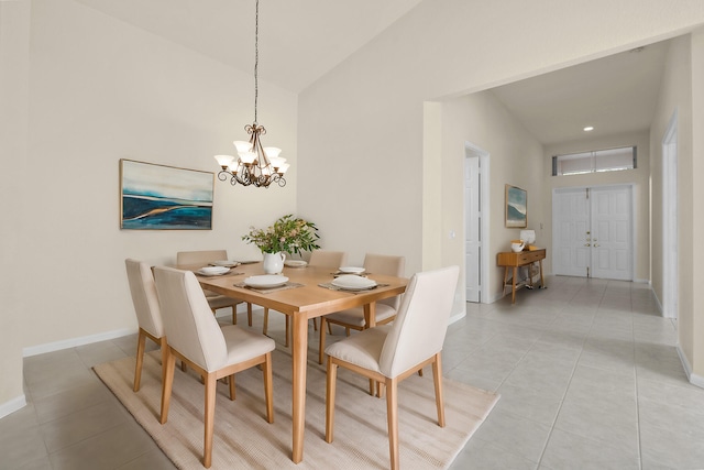 dining area with light tile patterned floors, vaulted ceiling, an inviting chandelier, and baseboards