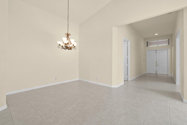 spare room with a chandelier, lofted ceiling, light tile patterned flooring, and baseboards