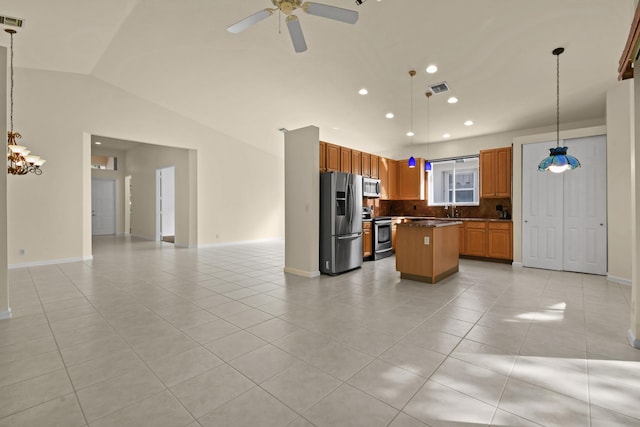 kitchen with stainless steel appliances, open floor plan, hanging light fixtures, a center island, and dark countertops