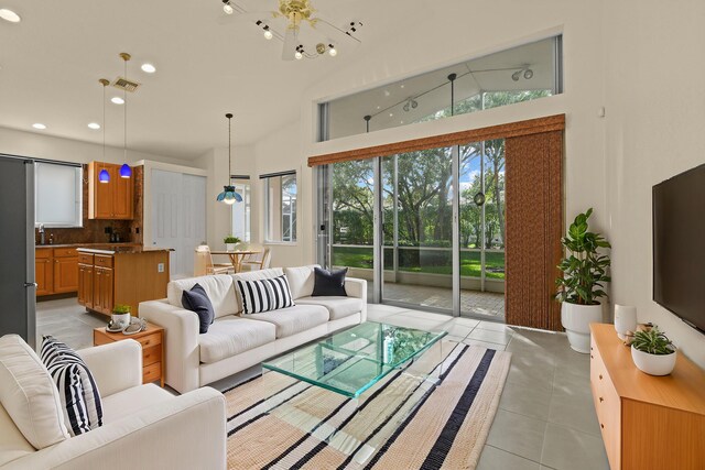 kitchen featuring hanging light fixtures, stainless steel fridge, lofted ceiling, decorative backsplash, and light tile patterned floors