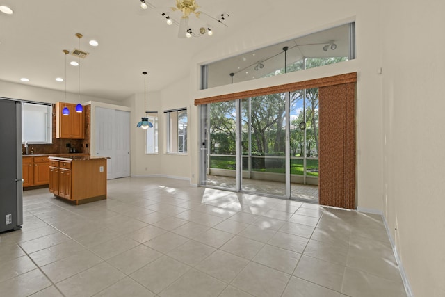 kitchen with pendant lighting, visible vents, brown cabinetry, open floor plan, and plenty of natural light