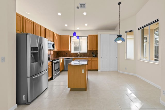 kitchen with appliances with stainless steel finishes, sink, light tile patterned floors, a kitchen island, and hanging light fixtures