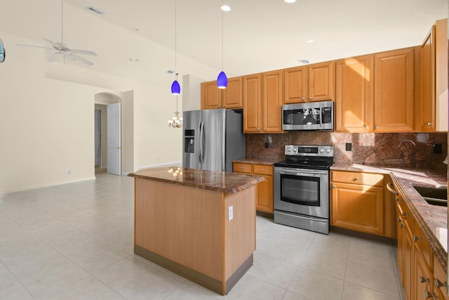 kitchen featuring decorative backsplash, appliances with stainless steel finishes, ceiling fan, light tile patterned floors, and a kitchen island