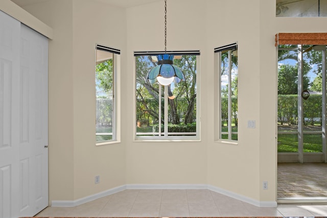 unfurnished dining area with light tile patterned flooring and baseboards