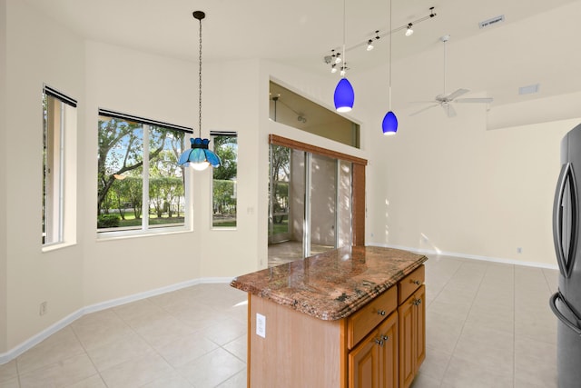 kitchen featuring high vaulted ceiling, a center island, hanging light fixtures, brown cabinets, and dark stone counters