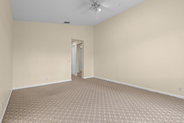 spare room with carpet floors, a ceiling fan, visible vents, vaulted ceiling, and baseboards