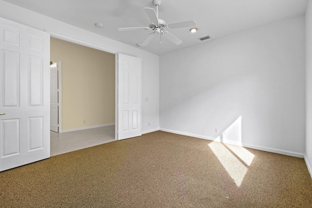 carpeted empty room with a ceiling fan, visible vents, and baseboards